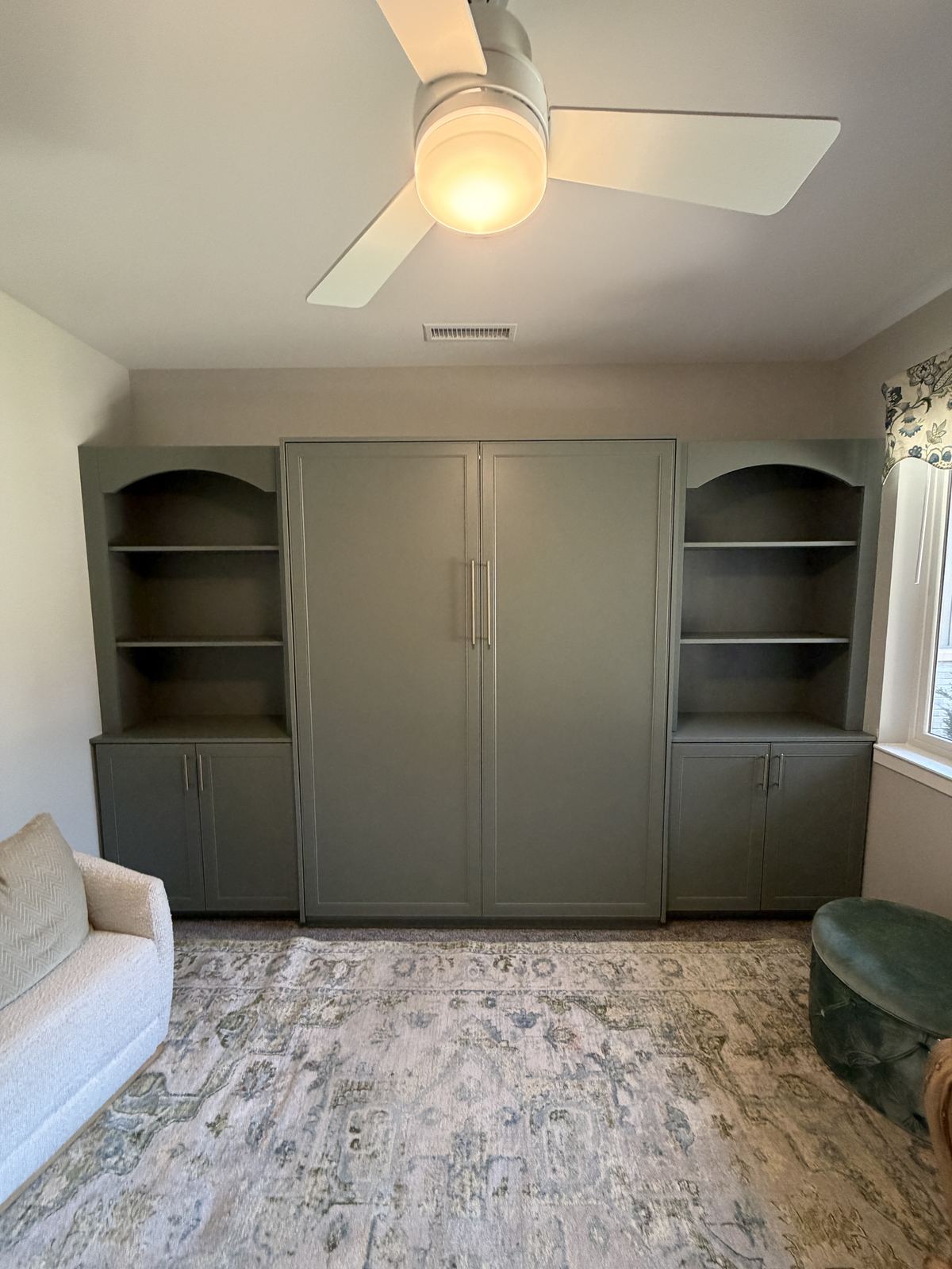 Sage green Murphy bed cabinet with arched open shelves and cabinets on each side