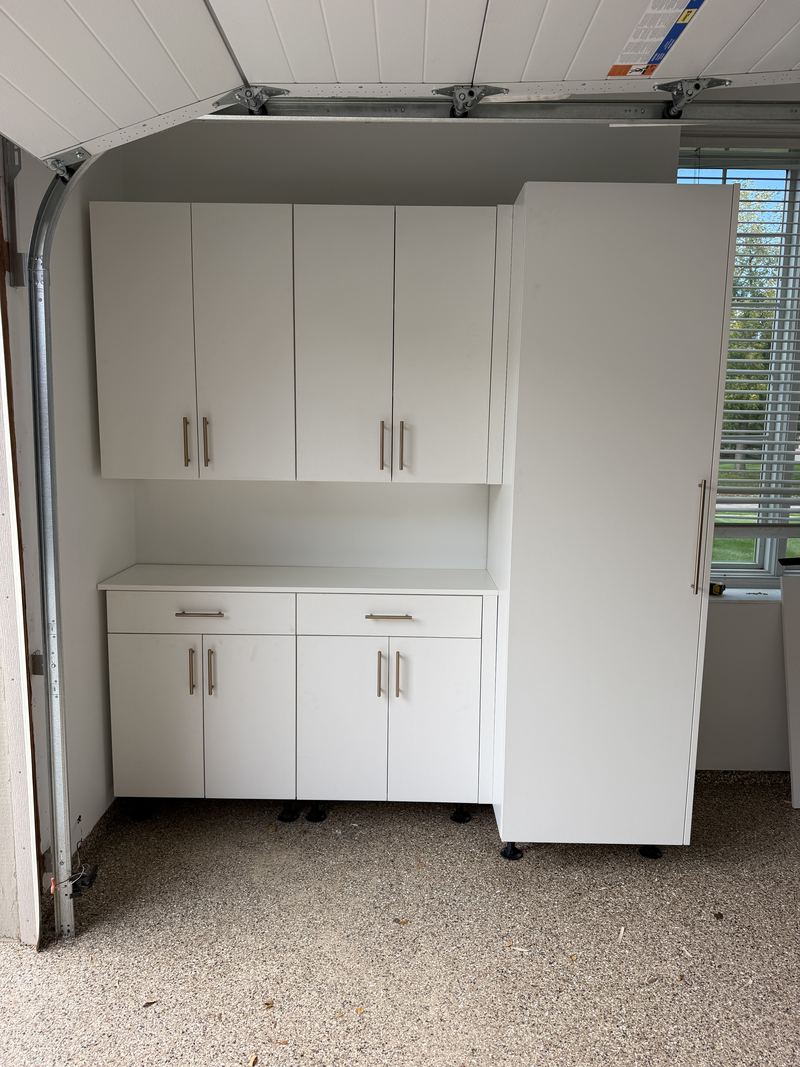 White garage wall and base cabinets with a tall pantry cabinet beside the garage door