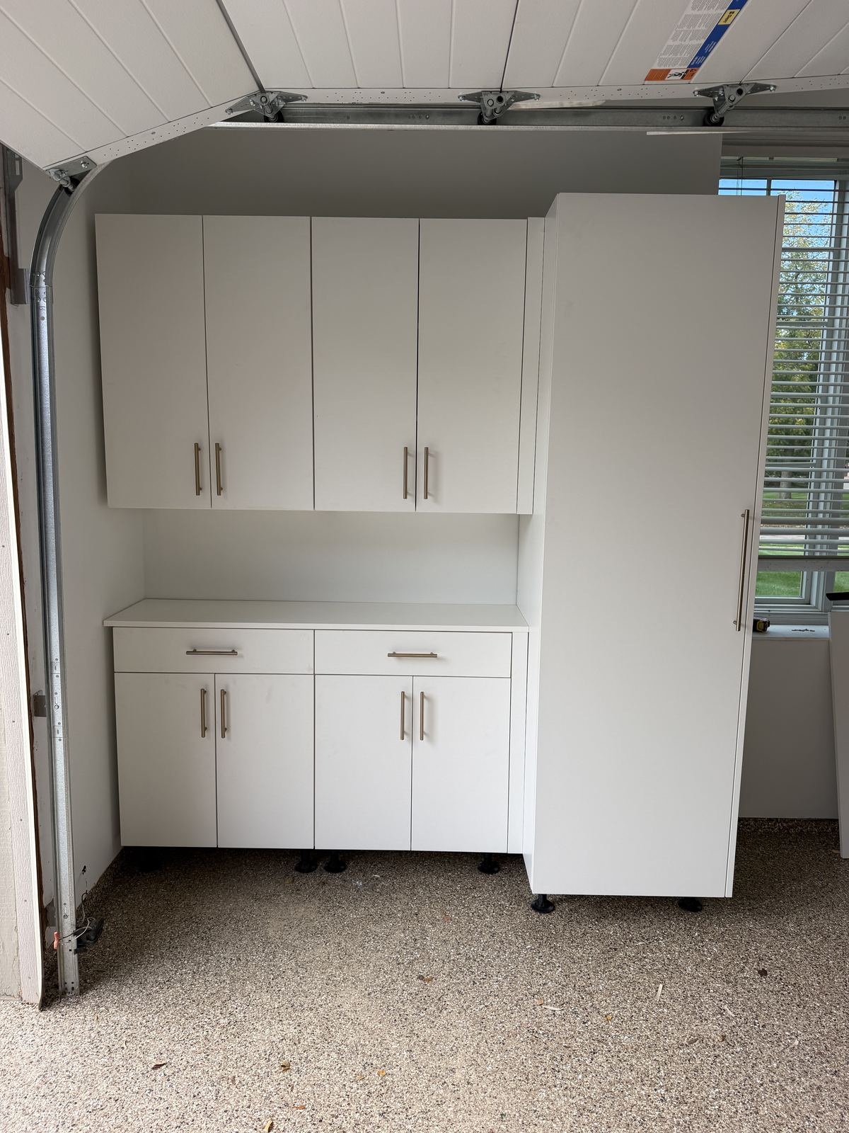 White garage wall and base cabinets with a tall pantry cabinet beside the garage door