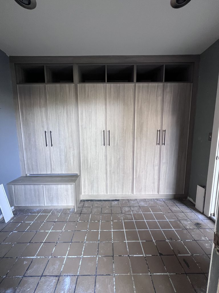 TrueForm mudroom in Saline with tall wood-look cabinet doors, open upper cubbies, and a bench with storage